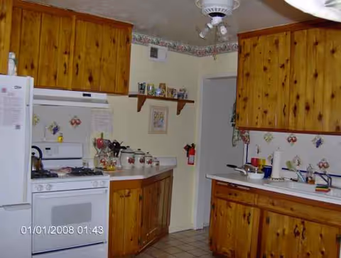 Wood-paneled kitchen with stove, sink, and countertops in a compact layout.