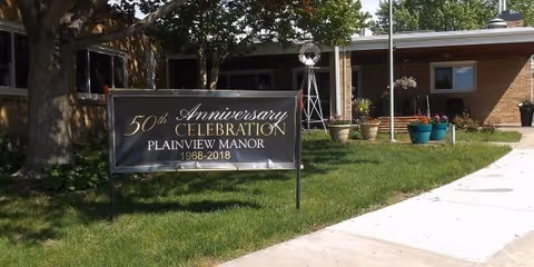 Exterior view of Plainview Manor with a 50th anniversary banner on the lawn.