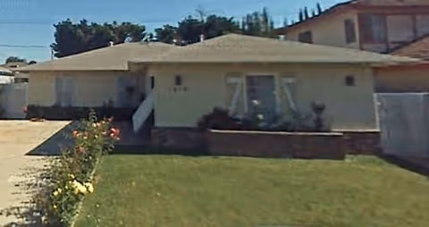 Front view of a single-story beige building with a grassy yard.