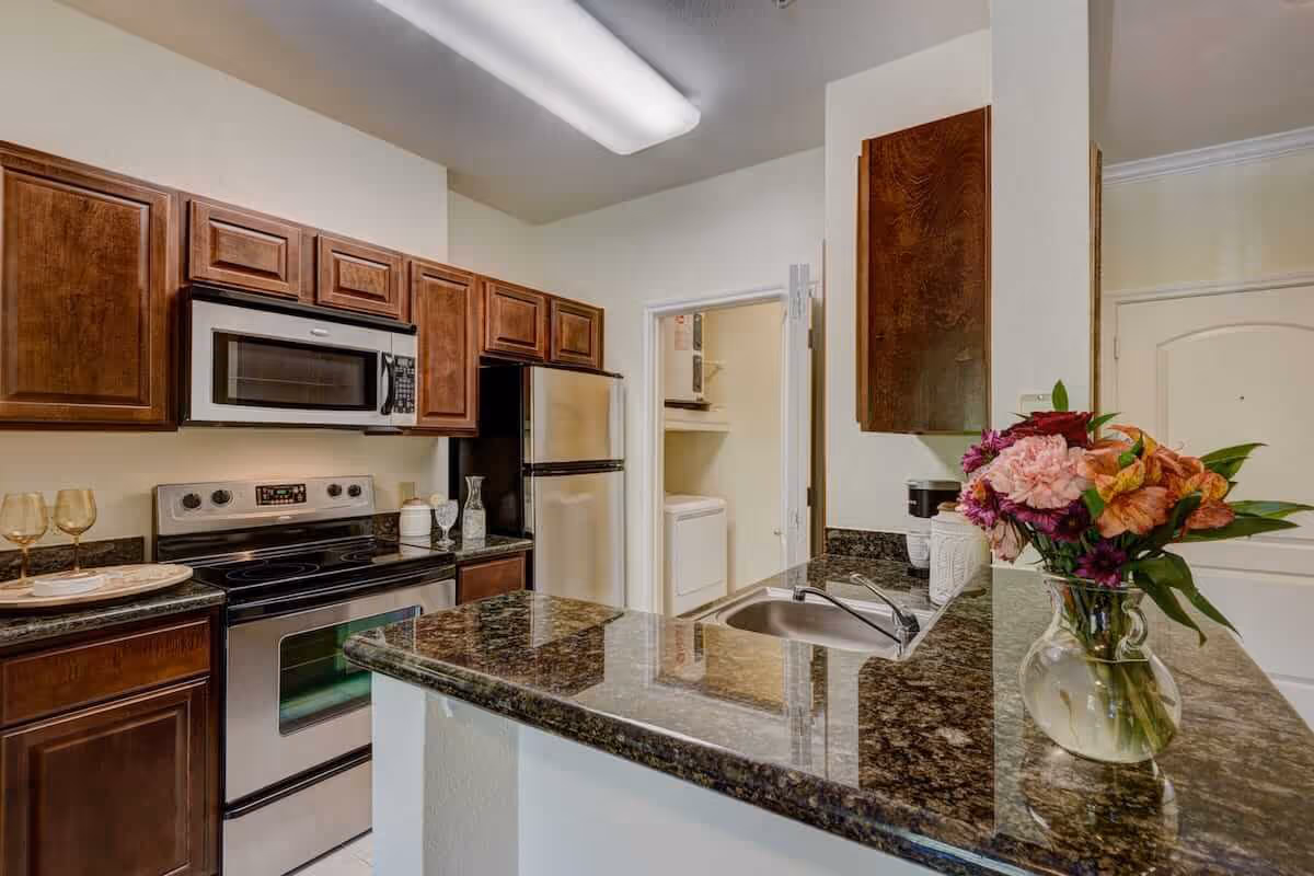 Modern kitchen with dark wood cabinets, stainless steel appliances, granite countertops and a vase of flowers on the counter.