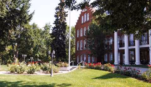 Front view of The Academy building with white columns and landscaped lawn