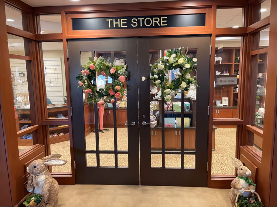 Double glass doors decorated with floral wreaths leading into 'The Store' gift shop with decorative bunny figures at the entrance.