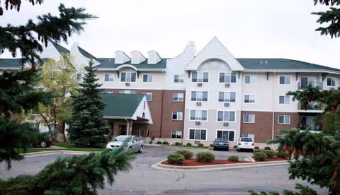 Exterior view of a retirement community with parked cars and manicured landscaping.