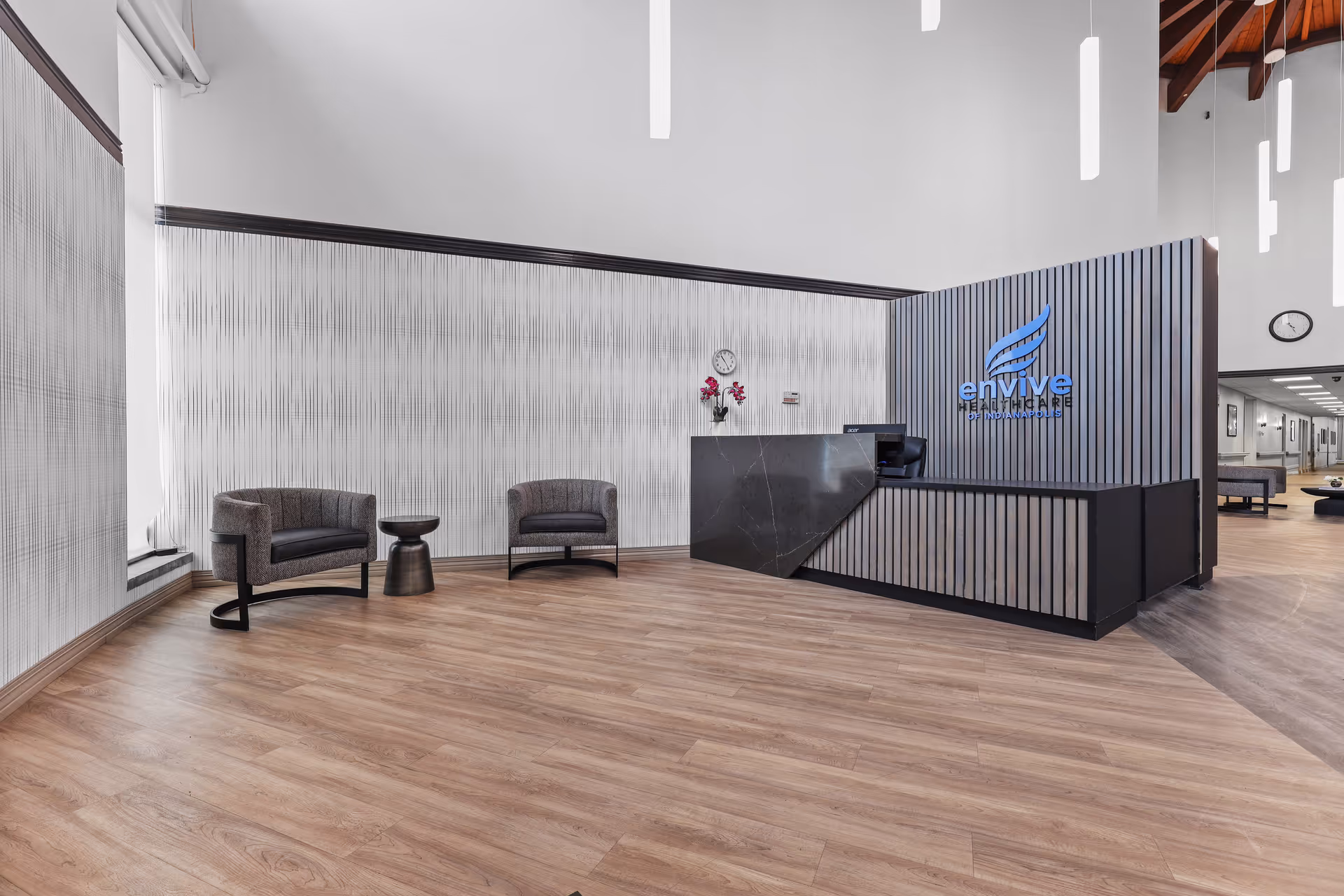 Modern reception lobby with two chairs and a small table beside a front desk bearing the Envive Healthcare logo.