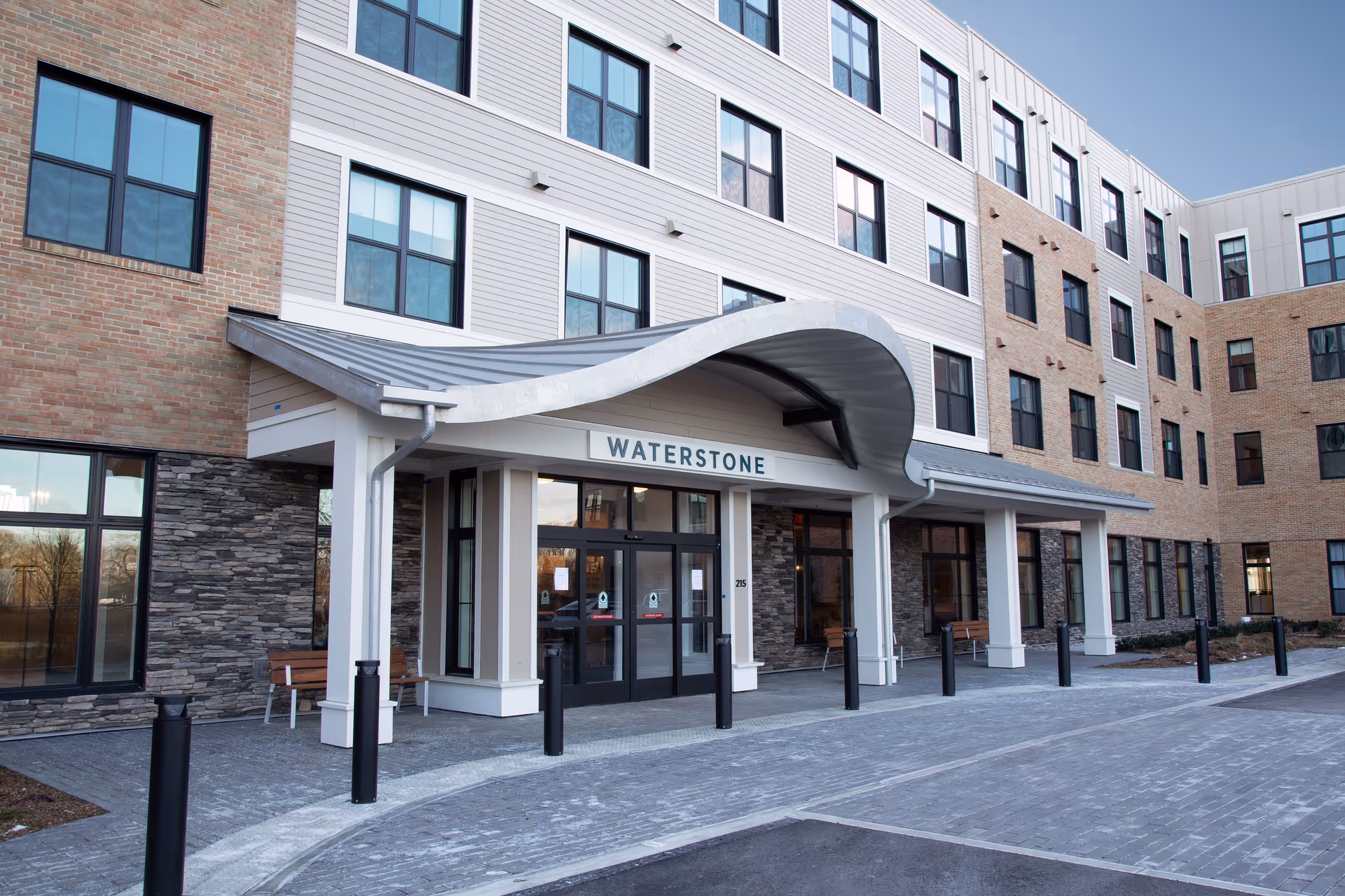Front entrance of the Waterstone senior living building with a curved canopy and multi-story windows.