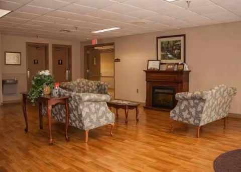 Cozy lounge with floral armchairs, wood floors, a fireplace, and a coffee table.