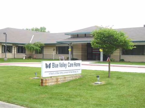 Front view of Blue Valley Care Home with sign on well-kept lawn.