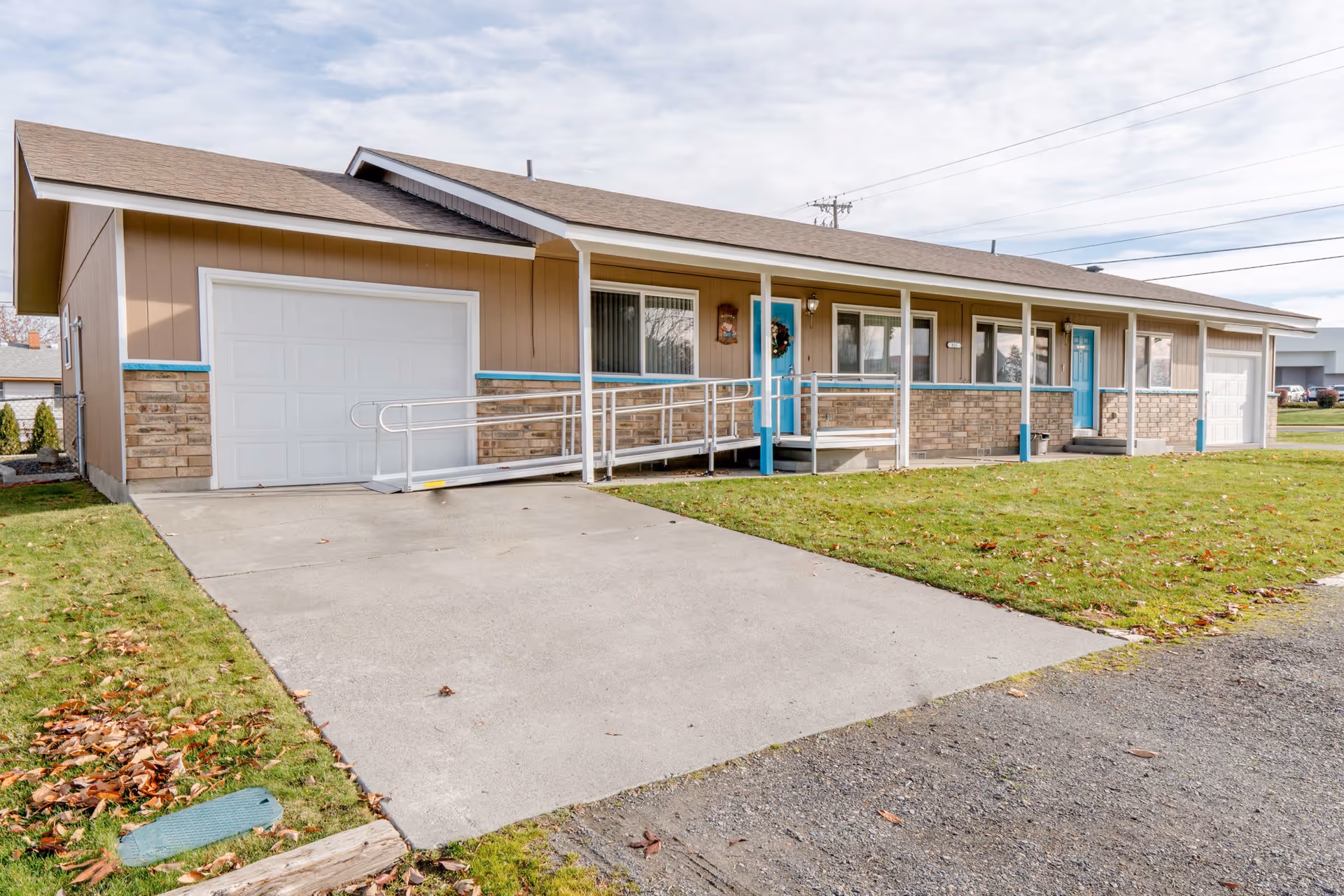 Single-story ranch-style house with an attached garage, front porch with a wheelchair ramp, and a grassy lawn.