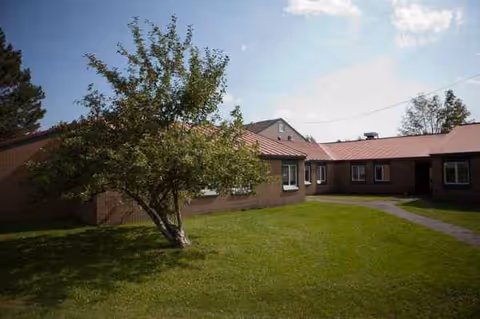 Exterior of Lakewood A Continuing Care Center, a brick single-story building with red roof and tree.
