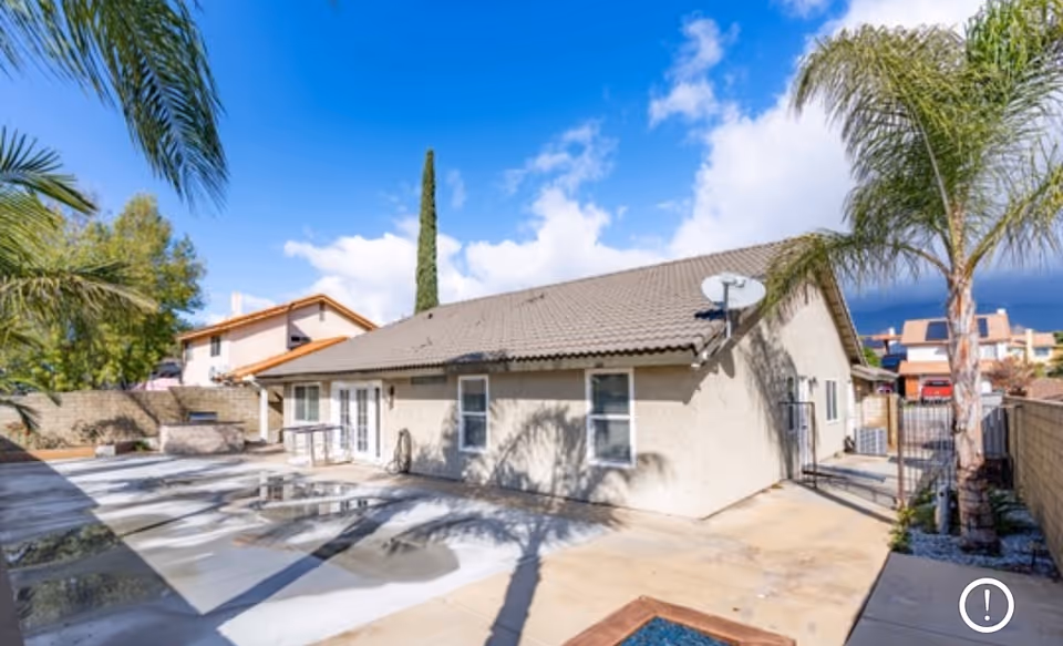 Single-story beige senior living facility exterior with palm trees and a paved courtyard.