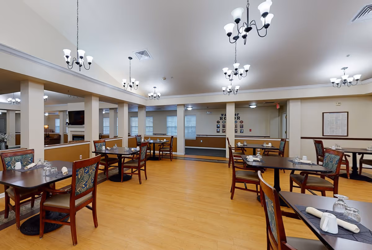 Spacious dining room with multiple set tables and chairs, chandeliers, and a wood floor.
