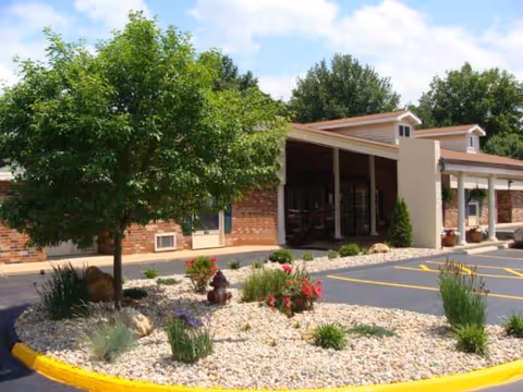 Exterior view of a senior living facility entrance with landscaped front yard.