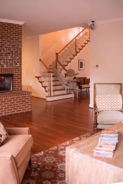 Cozy living room with brick fireplace, staircase, and comfortable seating.