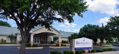 Brookdale Oakwell senior living facility entrance with sign, canopy, parking, and trees