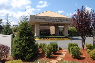 Front entrance of Somerset Gardens Senior Living with landscaped walkway and shrubs.