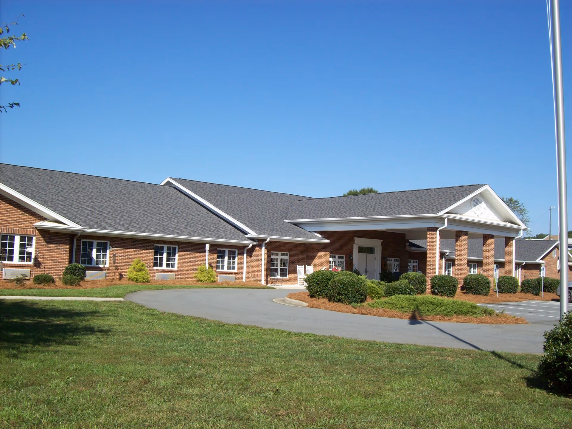 Brick exterior of an assisted living facility with a wide covered entrance and landscaped grounds.