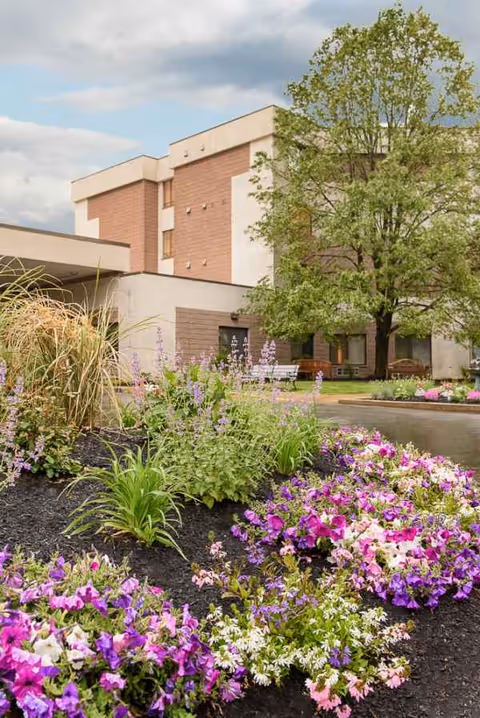 Exterior view of Life Care Center of the North Shore with landscaped flower beds and trees