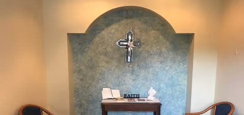 Altar with a cross and religious items against a blue arched wall.