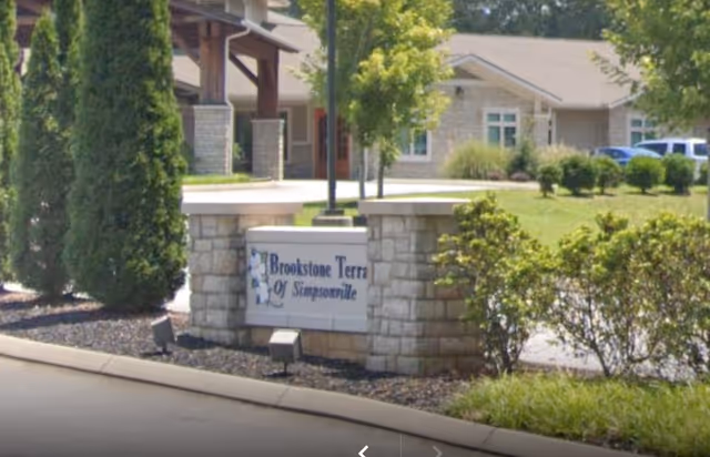 Stone entrance sign reading 'Brookstone Terrace of Simpsonville' with landscaped grounds and the facility building in the background.