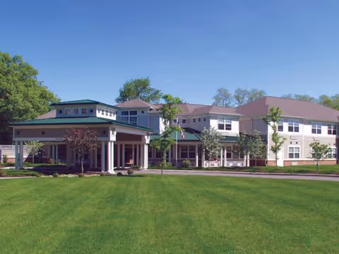 Front view of a large modern senior living facility with a green lawn