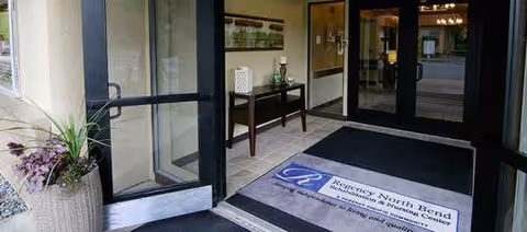 Entrance to Regency North Bend Rehab & Nursing Center with glass doors and welcome mat.