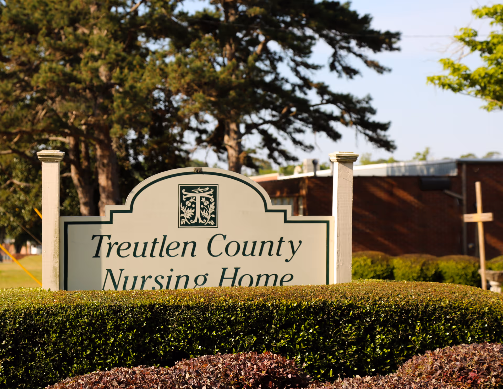 Sign for Treutlen County Nursing Home surrounded by bushes and trees.