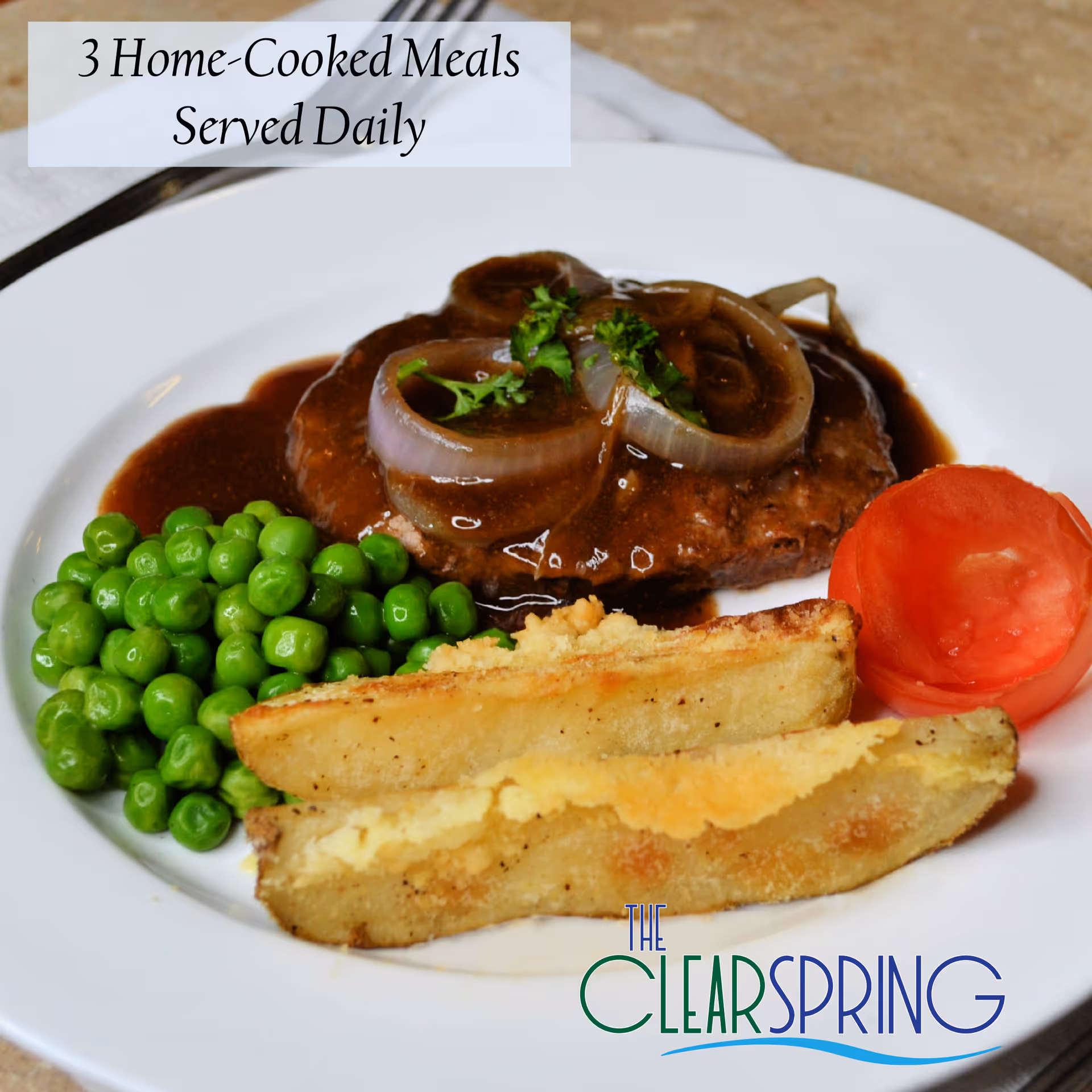 Plate of beef with onion gravy, peas, potato wedges, and a tomato slice.