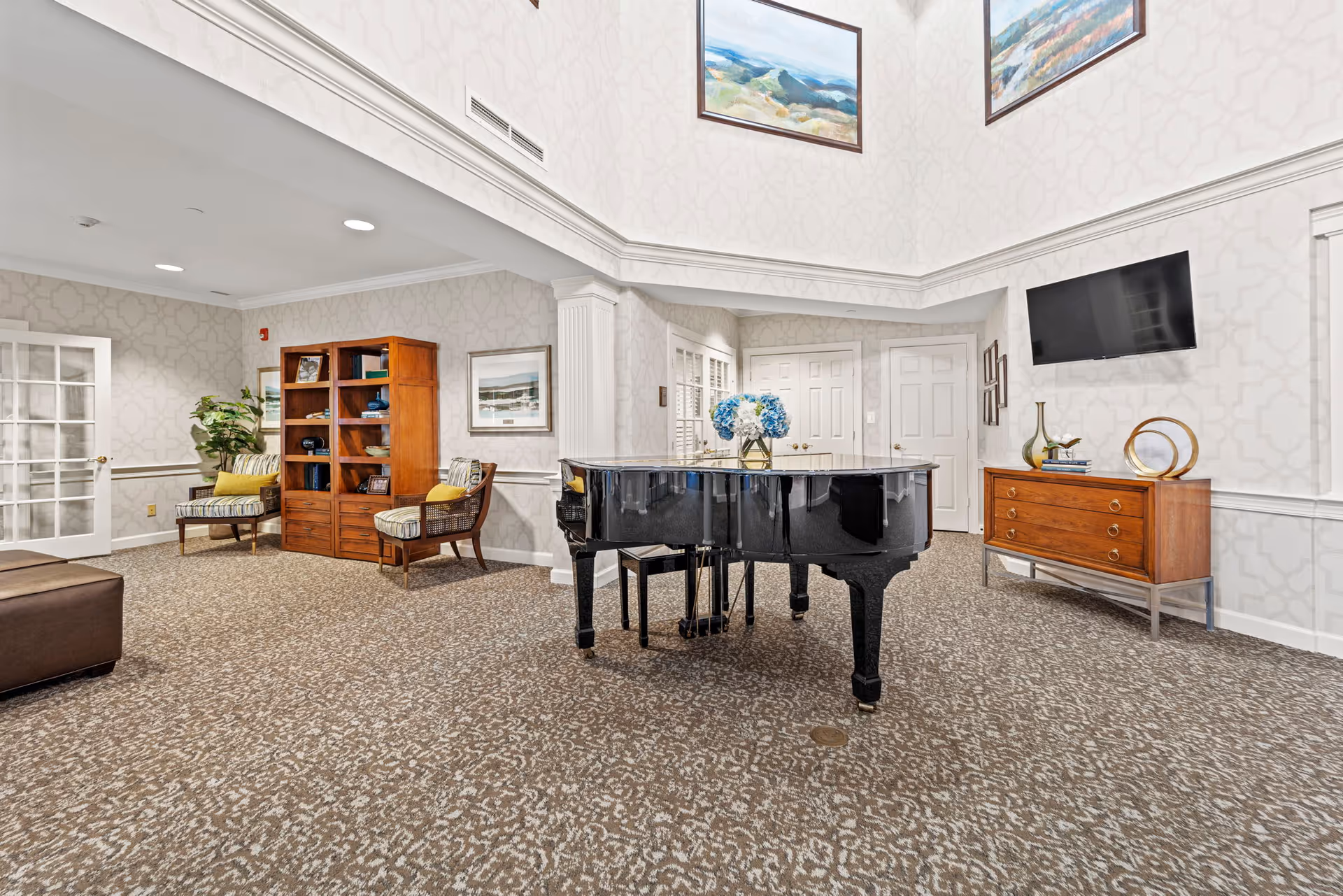 Spacious senior living lounge with a black grand piano at center, seating, bookshelf, TV, and decorative accents.
