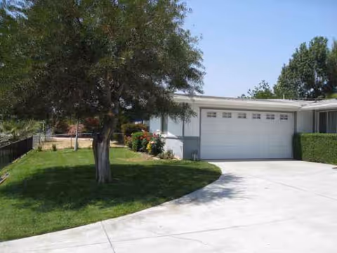 Front view of a single-story elderly care facility with a two-car garage and green lawn.
