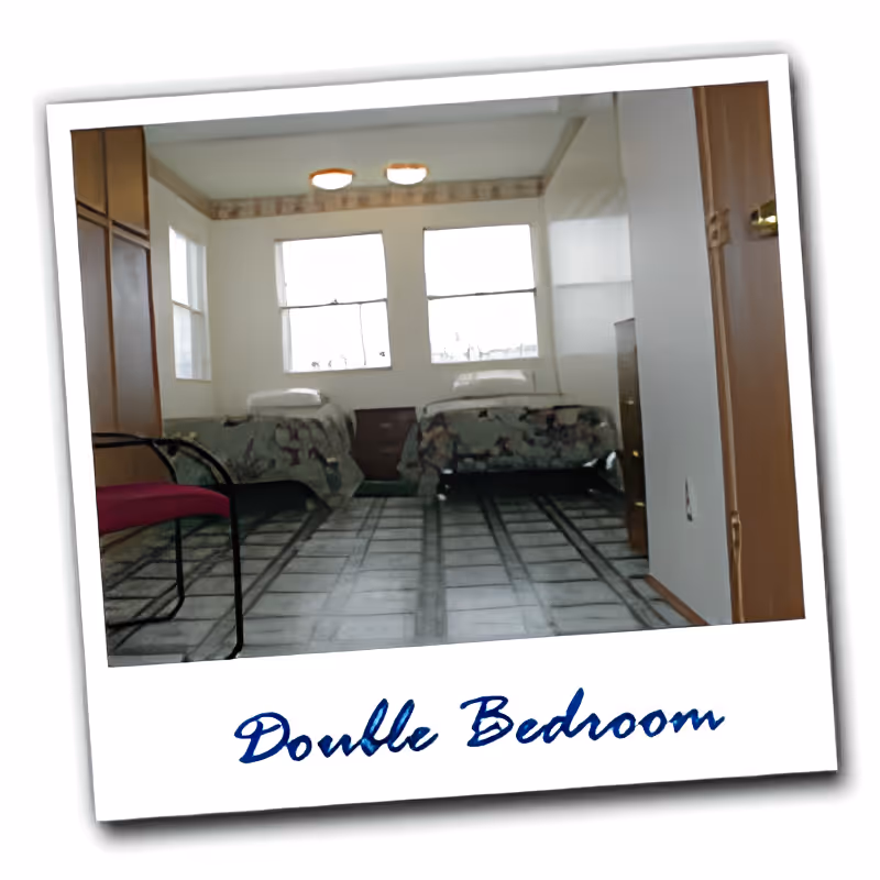 Small bedroom with two twin beds, a chair, three windows, and a framed caption reading 'Double Bedroom'.