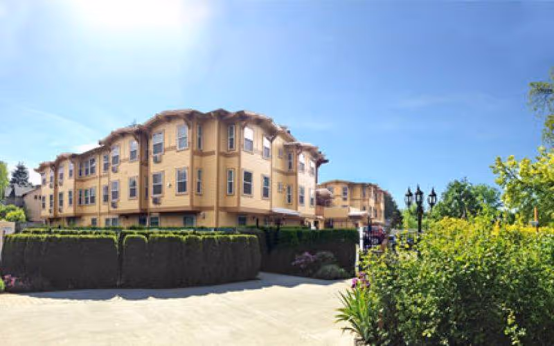 Exterior view of Elite Care at Fanno Creek building with hedges and clear sky.