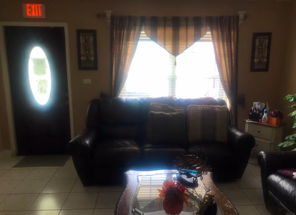 Living room with leather sofa, decorative pillows, coffee table, and exit door.