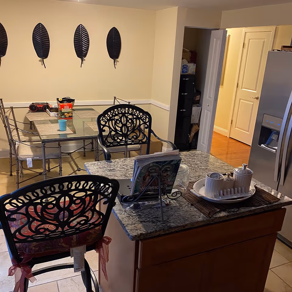 Bright dining area with glass table, metal chairs, and a nearby kitchen island.