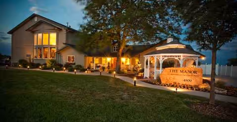 Evening view of The Manor on Marston Lake exterior with illuminated entrance and gazebo.