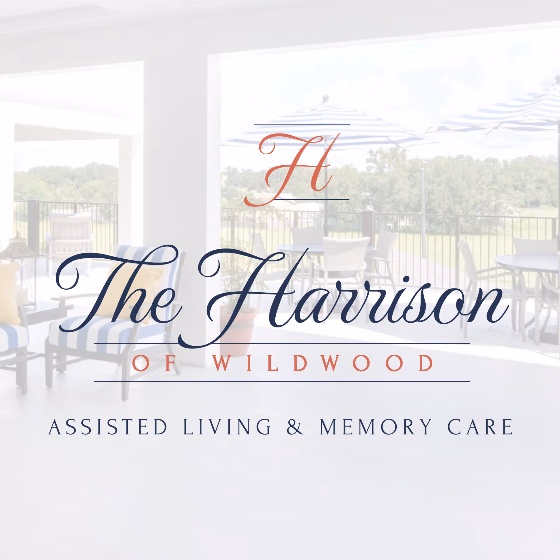 Outdoor patio area with chairs, tables, and striped umbrellas overlooking a green landscape, with a semi-transparent overlay of The Harrison of Wildwood logo and text 'Assisted Living & Memory Care'.