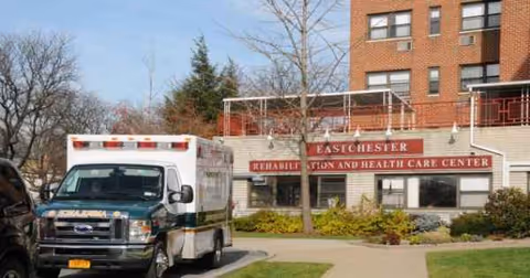 Ambulance parked in front of a rehabilitation and health care center building.