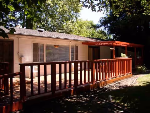 Single-story elderly care home with a wooden deck and shaded front yard.