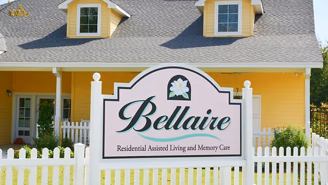 Yellow residential facility exterior with a Bellaire sign and white picket fence
