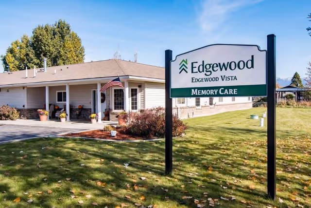 Front exterior of the Edgewood Edgewood Vista Memory Care building with a lawn, entrance, and a large sign.
