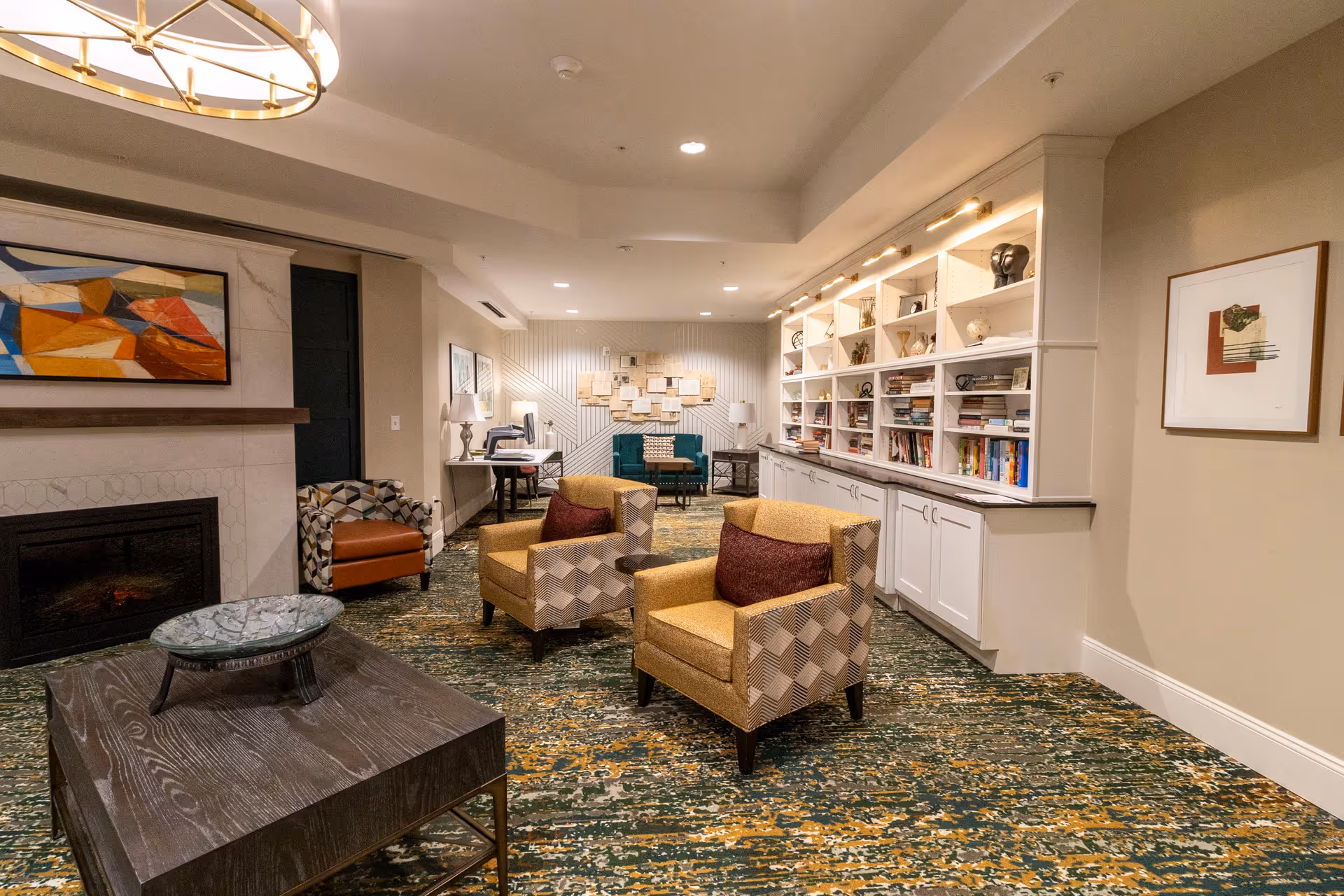 Comfortable common room with armchairs, a coffee table, built-in bookshelves, and a fireplace.