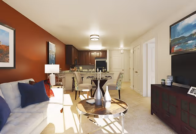 Bright living room and dining area with a sofa, coffee table, TV console and an open kitchen in the background.