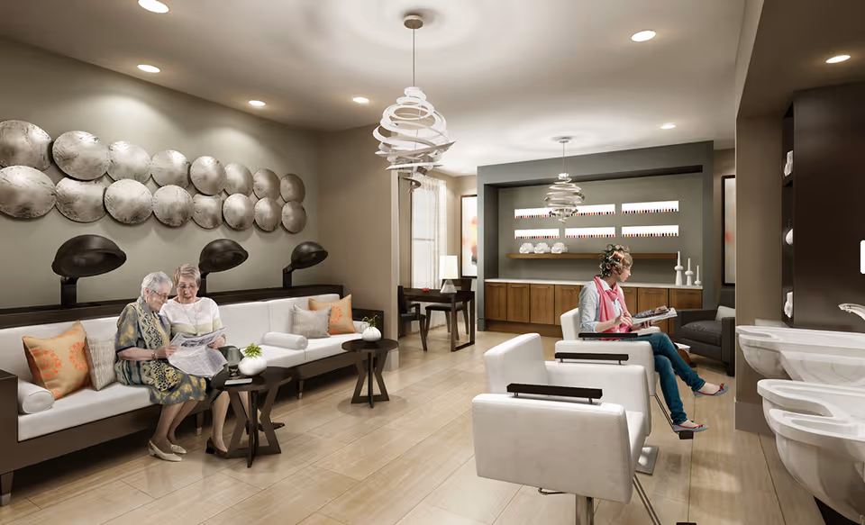 Bright, modern salon-style common room with seating, hair-dryer stations, and residents reading magazines.