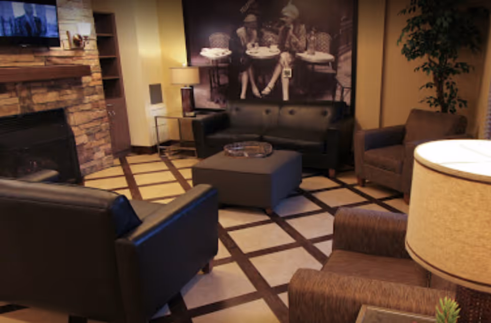 Comfortable lounge with leather sofas, armchairs, a central ottoman and a fireplace.