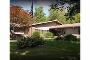 Single-story building with a flagpole and landscaped front yard.