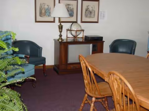 A dining room with a large wooden table, chairs, and a sideboard against the wall.