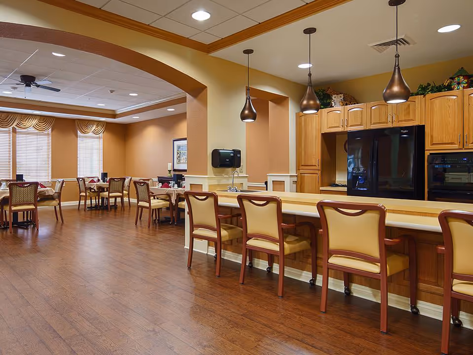 Interior view of the dining room at Legend of Fort Worth, featuring wooden flooring, tables set for dining, and a warm color scheme with decorative lighting.