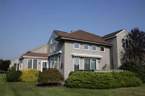 Exterior of Medford Leas senior living facility with shrubs and clear sky.