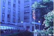 Entrance of a multi-story healthcare building with an American flag, covered walkway, and landscaping.