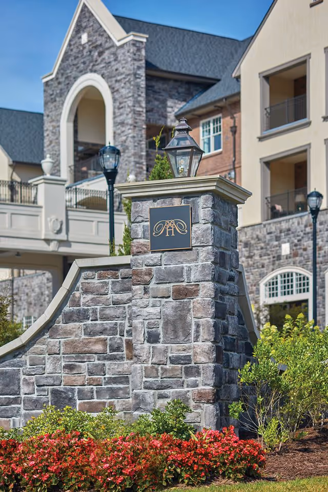 Front view of The Terraces at Peachtree Hills Place entrance with stone pillar and lodge-style facade
