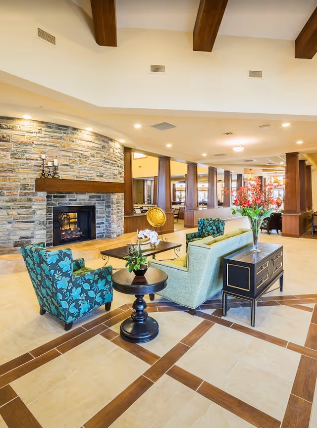 Spacious lobby lounge with sofas and armchairs arranged around a coffee table in front of a stone fireplace.